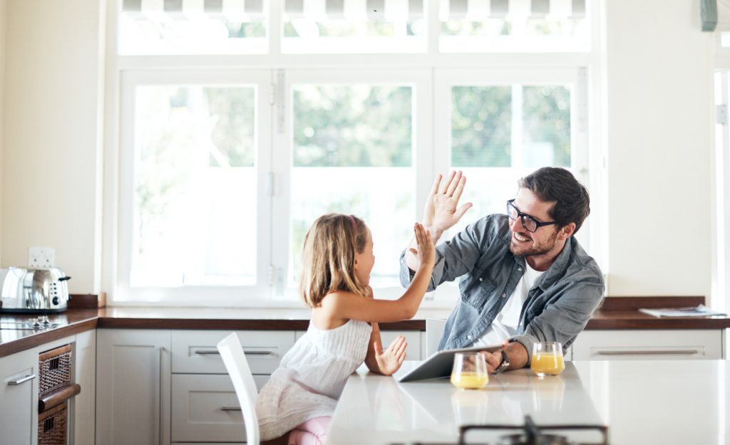 Father and daughter high fiving in the family kitchen