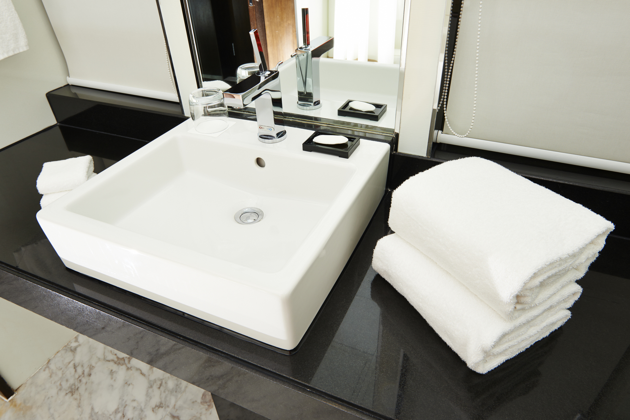 A luxury bathroom with ceramic wash basin and chrome faucet.